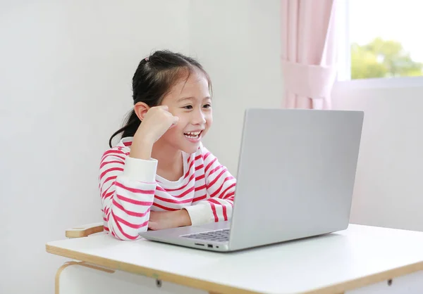 Masada Oturan Asyalı Küçük Kız Dizüstü Bilgisayarda Çizgi Film Izlemenin — Stok fotoğraf