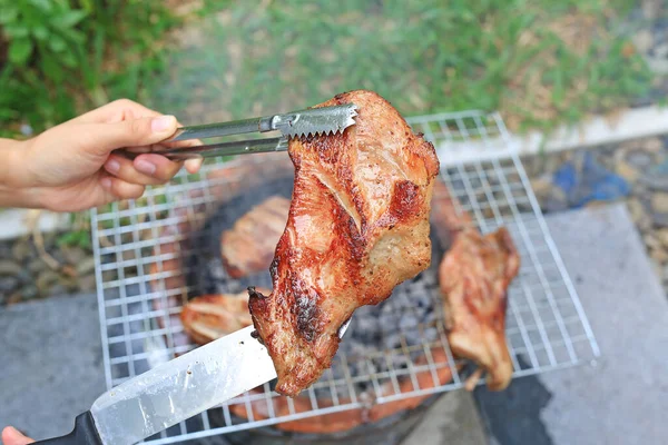 炭火焼ストーブの上にバーベキューの手を保持作品 グリルでおいしい豚肉を焼きます — ストック写真