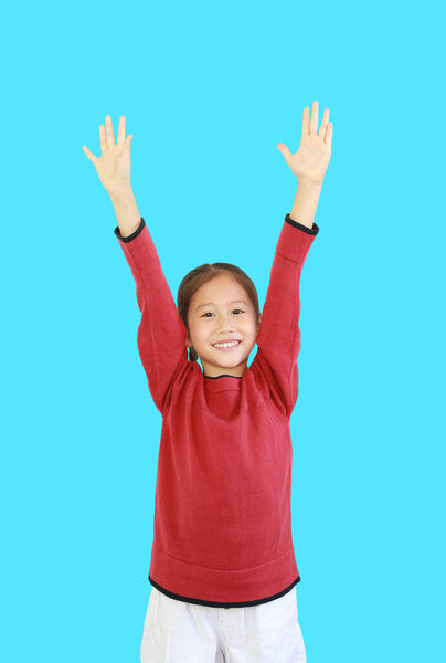 Cheerful asian little kid girl in red long sleeve shirt holding hands up isolated on cyan background. Student question and answer concept
