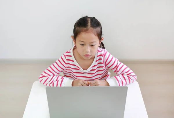 stock image Intend asian little child sitting at desk and using laptop at home