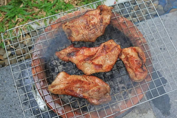 炭火焼ストーブの上のバーベキューの作品 煙とグリルでおいしい豚肉を焼きます — ストック写真