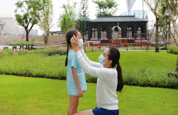 アジアのお母さん身に着けています保護顔マスクのために女の子子供のための公共の庭でCoronavirusとインフルエンザ発生中 — ストック写真