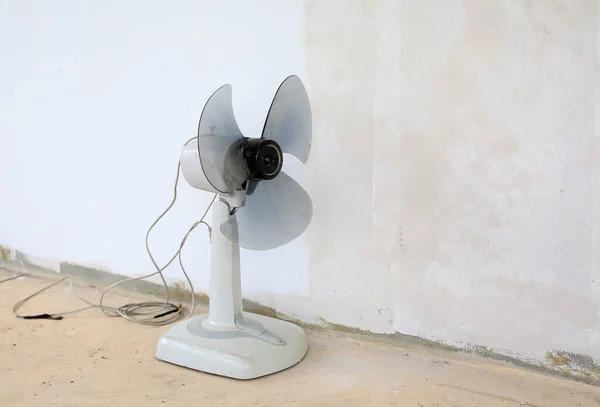 Old electric fan against dirty white concrete wall background