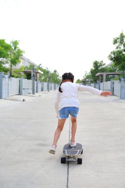 Çocuk sokakta kaykayla geziyor. Arka plan