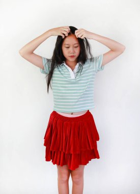 Güzel elbiseli Asyalı bir kızın portresi saçını şekillendiriyor, çocuk ellerini beyaz arka plana dayayıp saçını düzenliyor..