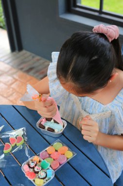 Pasta yapan ve dekore eden Asyalı kız çocuğu portresi..