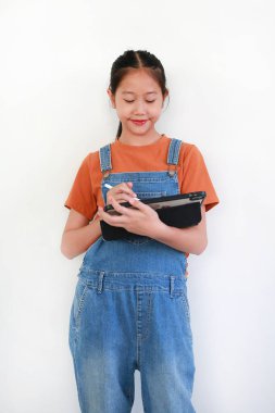 Asyalı kız elinde tablet ve stil tutarken beyaz arka plana karşı yaratıcı ya da eğitici bir proje üzerinde çalışıyor, yazıyor ya da çiziyor..