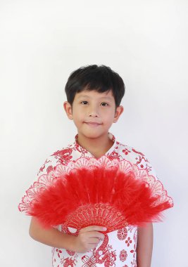 Beyaz ejderha desenli tişörtlü yakışıklı Asyalı çocuk Çin Yeni Yılı 'nı kutluyor, yumuşak bir gülümsemeyle poz veriyor ve elinde dekoratif kırmızı pervane tutuyor..