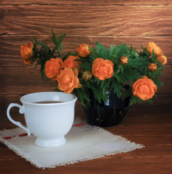 Натюрморт с цветами и чашкой чая на деревянном фоне — стоковое фото
