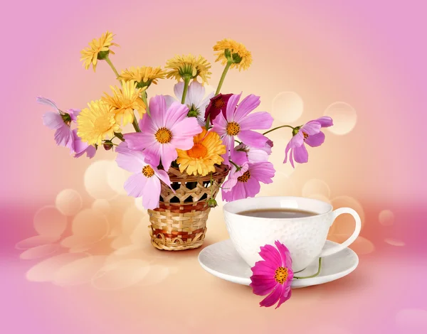 Summer flowers and a cup with a drink on a bright background of the warm — Stock Photo, Image