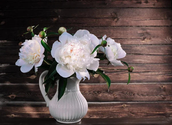 Peônias brancas em um vaso em um fundo de madeira — Fotografia de Stock