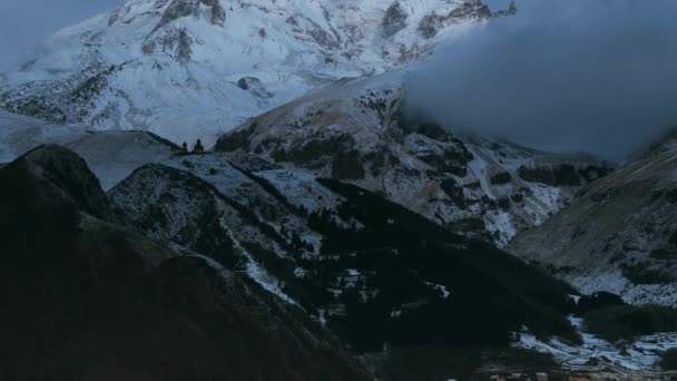 Stepantsminda, Gergeti, Georgia. Monte Kazbek cubierto de nieve en el amanecer de invierno. Mañana amanecer coloreado cima de la montaña en colores rosados. Impresionante paisaje natural georgiano de invierno. Tiempo de caducidad Timelapse 4K — Vídeo de stock