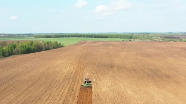 4K Aerial Flat View Tractor Plowing Field In Spring Season. Začátek zemědělské jarní sezóny. Kultivátor tažený traktorem v krajině venkovského pole. Ptáci v hejnu po — Stock video