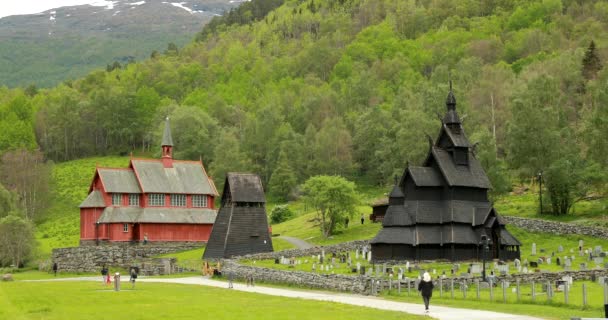 ノルウェーのボルグンド- 6月14 、 2019:有名なノルウェーのランドマークStavkirkeの近くを歩く人々夏の日に古い木造の三重身廊教会。ズームアウト、ズームアウト。4K — ストック動画