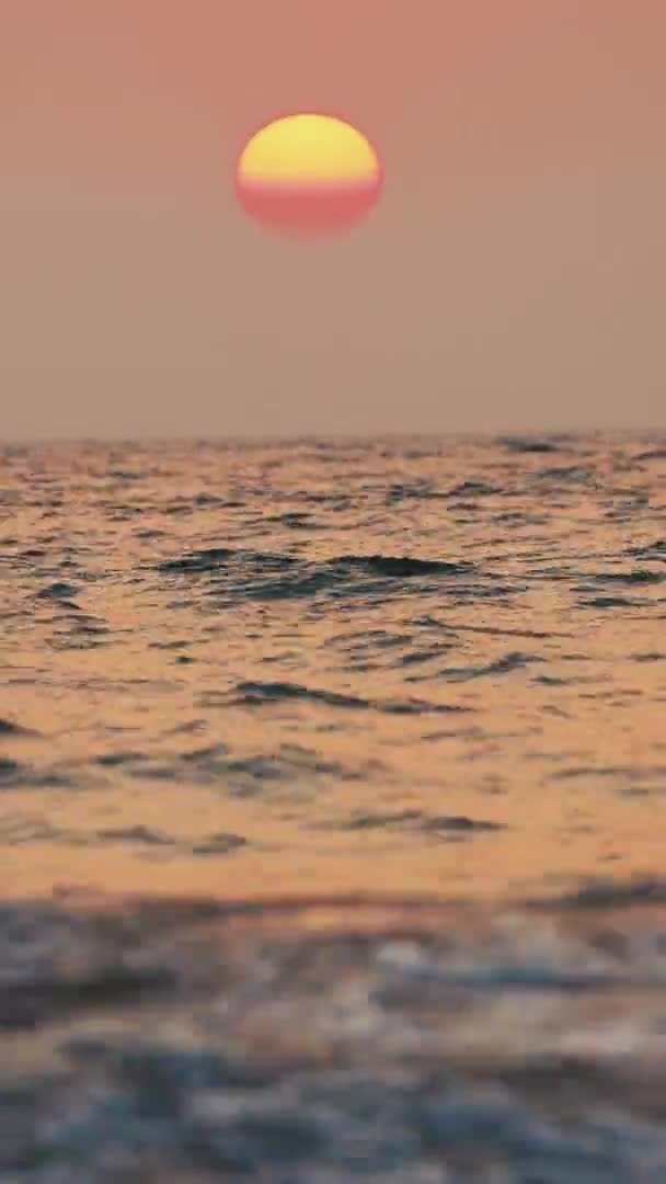 Ηλιοβασίλεμα πάνω από τη θάλασσα. Φυσικό ουρανό ζεστά χρώματα πάνω από τη θάλασσα κυματισμός. Θαλασσινό νερό Αφρός Splash πλύσιμο αμμώδη παραλία στο ηλιοβασίλεμα. Κάθετη. — Αρχείο Βίντεο