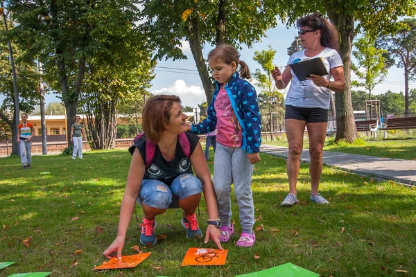 Los padres con niños jugando varios juegos en la hierba, en el parque en el centro de la ciudad — Foto de Stock