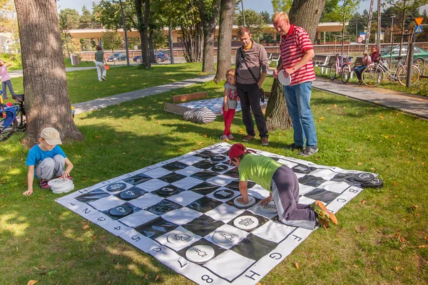 Parents with children playing various games on the grass, in the park in city center — Stock Photo, Image