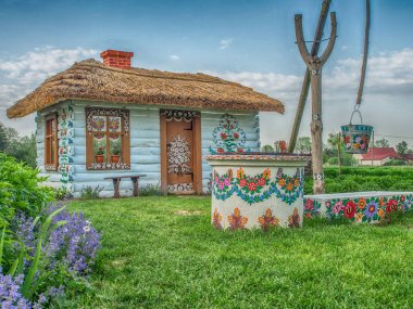 Zalipie, Poland - May 20, 2017: Colourful house with flowers painted on  walls and sundial  in the village of Zalipie in Malopolska, spring time clipart