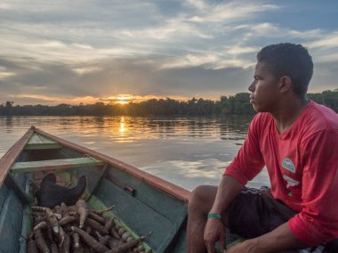 Jungle, Brazil - Dec 7, 2017:  Portrait of a man with a red skin sitting on the boat on the backgroud of sun set.  Amazon  jungle