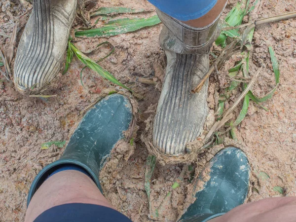 Two people standing on a mud in the long wellington boots. Summer time in the jungle. Amazon.