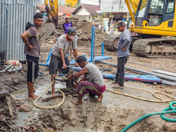 Ambon, Endonezya - 17 Şubat 2018: Ambon caddesinde su pompalayan işçiler.