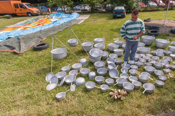 Un hombre vendiendo ollas de metal exhibidas en la hierba —  Fotos de Stock