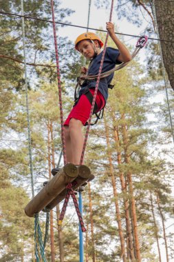 Emniyet kemeri ve ip Park'ta yürüyordunuz kask giymiş bir çocuk.
