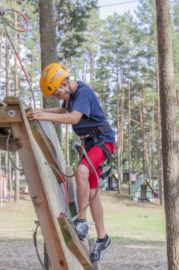 Emniyet kemeri ve ip Park'ta yürüyordunuz kask giymiş bir çocuk.