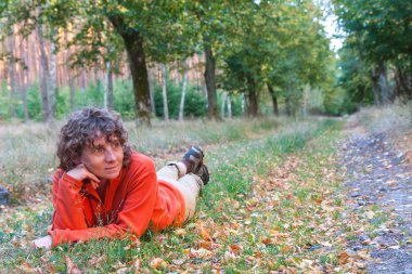Bir orman yolu kenarında oturan orta yaşlı kadın.