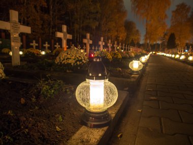 Alley of graves with lighted candles in a Catholic cemetery clipart