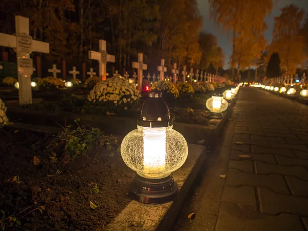 Gräberallee mit brennenden Kerzen auf einem katholischen Friedhof — Stockfoto