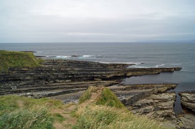 Mullaghmore Head 'e giderken, Mullaghmore' un güzel kumsal ve rıhtımının yanından geçiyorsun. Kasabadan hemen sonra, dalgalar sakin kıyı şeridine doğru ilerliyor..