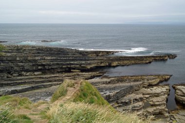 Mullaghmore Head 'e giderken, Mullaghmore' un güzel kumsal ve rıhtımının yanından geçiyorsun. Kasabadan hemen sonra, dalgalar sakin kıyı şeridine doğru ilerliyor..