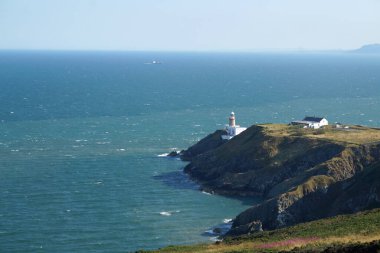 Howth kasabası, Sutton 'ın Dublin bölgesinin tam karşısındaki Howth Head yarımadasında yer almaktadır ve bir baraj yoluyla anakaraya bağlıdır. Baily Deniz Feneri bir promoner üzerinde duruyor ve Howth Tepesi 'nden çok iyi görünüyor..