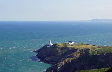 Howth kasabası, Sutton 'ın Dublin bölgesinin tam karşısındaki Howth Head yarımadasında yer almaktadır ve bir baraj yoluyla anakaraya bağlıdır. Baily Deniz Feneri bir promoner üzerinde duruyor ve Howth Tepesi 'nden çok iyi görünüyor..