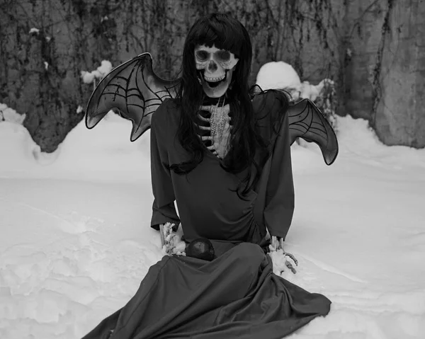 Devil bride skeleton with red dress and devil wings in snow