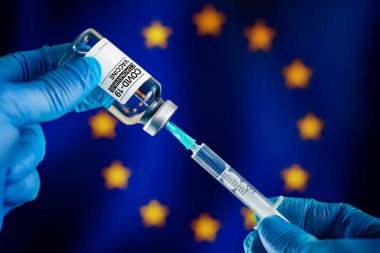 Doktor Avrupa ülkelerinde Coronavirus aşısı için ilaç şişesi hazırlıyor. Avrupa bayrağı üzerinden Covid-19 için şırıngaya aşı enjekte ediliyor