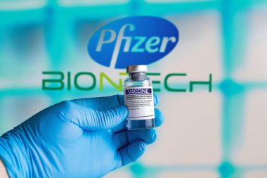 Madrid, Madrid, İspanya - 21 Nisan 2021. Coronavirus aşısı için Pfizer-BioNTech aşısı. Arkaplanda Pfizer ve Biontech şirketleri var. Aşı şirketi Pfizer BioNTech 'in ürünü.