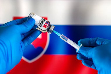 Doktor, Slovakya 'daki hastalıklara karşı aşı için aşı enjeksiyonu şişesi hazırlıyor. Enfeksiyonları önlemek için şırıngaya aşı enjekte etmek Slovakya bayrağı önünde