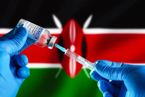 Doctor preparing vial of vaccine injection for the vaccination plan against diseases in Kenya. Injecting dose of vaccine in syringe for infections prevention in front of the Kenya flag