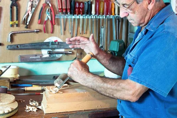 Retrato de ebanista tallando una pieza de madera con cincel y — Foto de Stock