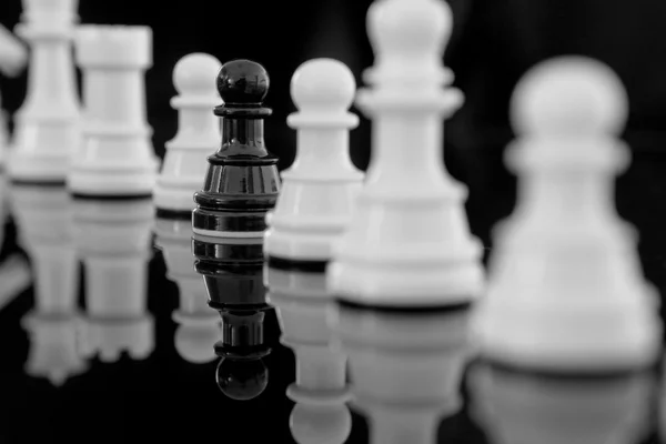 Черная пешка среди белых шахмат Стоковое Изображение