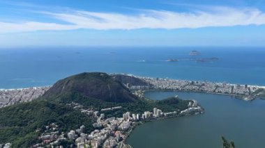 Corcovado 'dan Rio de Janeiro' nun panoramik görüntüsü, Sugarloaf Dağı, Guanabara Körfezi, Santos Dumont Havalimanı ve Atlantik kıyı şeridi parlak, parçalı bulutlu hava altında.