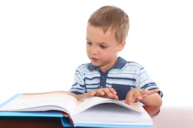 Okul öncesi küçük çocuk beyaz bir arkaplan üzerine kitap okuyor. Odaklanma ve merakını gösteriyor..