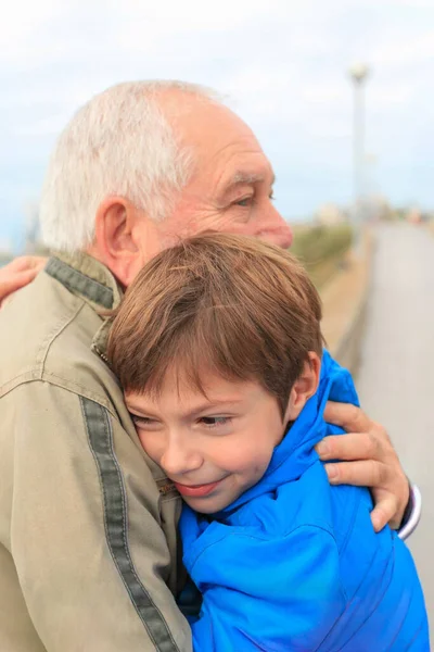 Küçük torununu kucaklayan bir büyükbabanın yakın plan portresi.. 