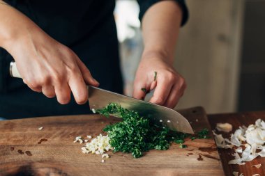 Maydanoz doğrayan bir şefin yakın plan fotoğrafı.
