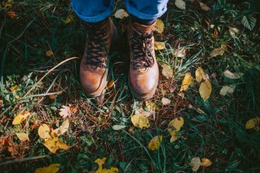 Çimenli ve yapraklı deri botların üstünden.