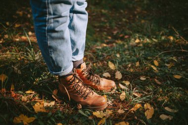Çimenli ve yapraklı deri botların üstünden.