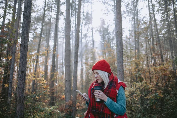 女背包客在森林里喝咖啡 用手机发短信 — 图库照片