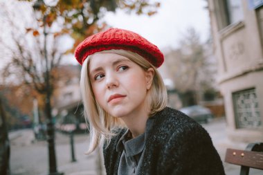 Genç değişim öğrencisi eski kasabada bir kitap okuyor. Kırmızı bereli Avrupalı bir kadın açık havada kitap okuyor..